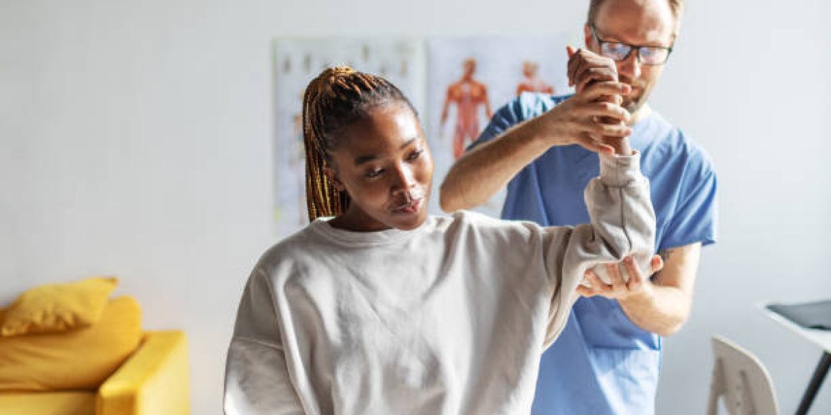 Physical therapist helping young black woman with her shoulders